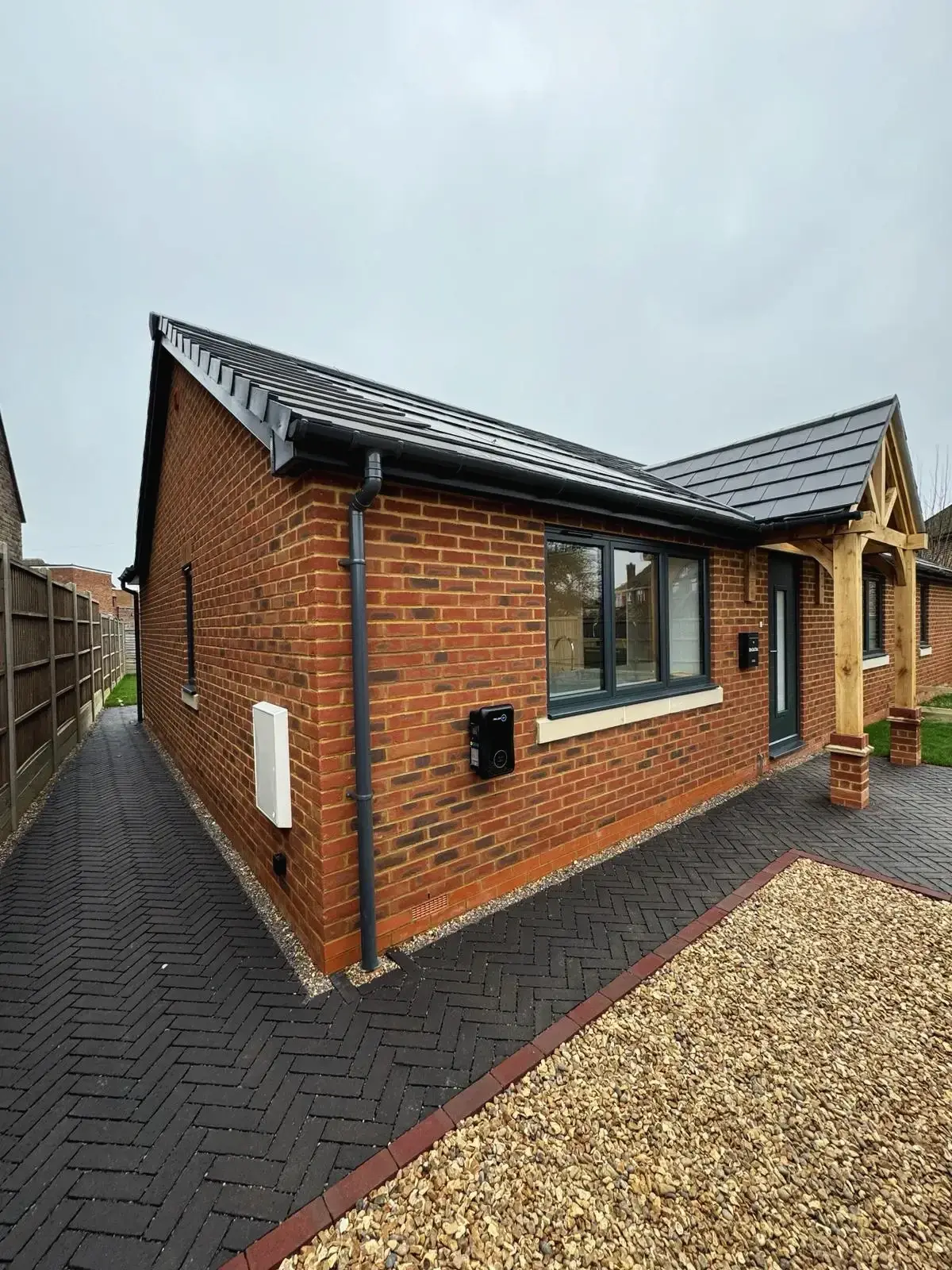 Another side view of modern brick bungalow with paved pathway and oak porch