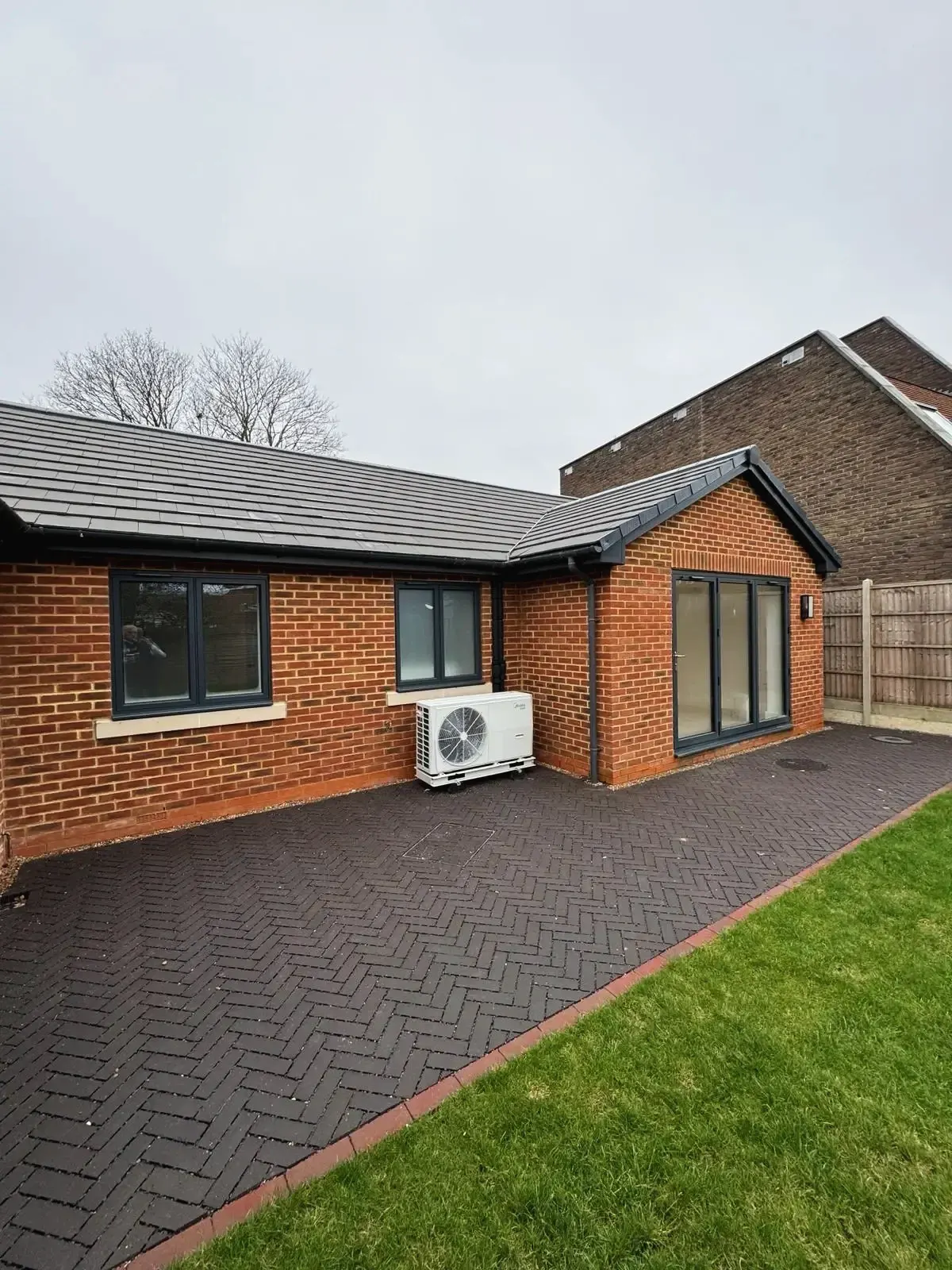 Back exterior of new build property with paved patio and garden view