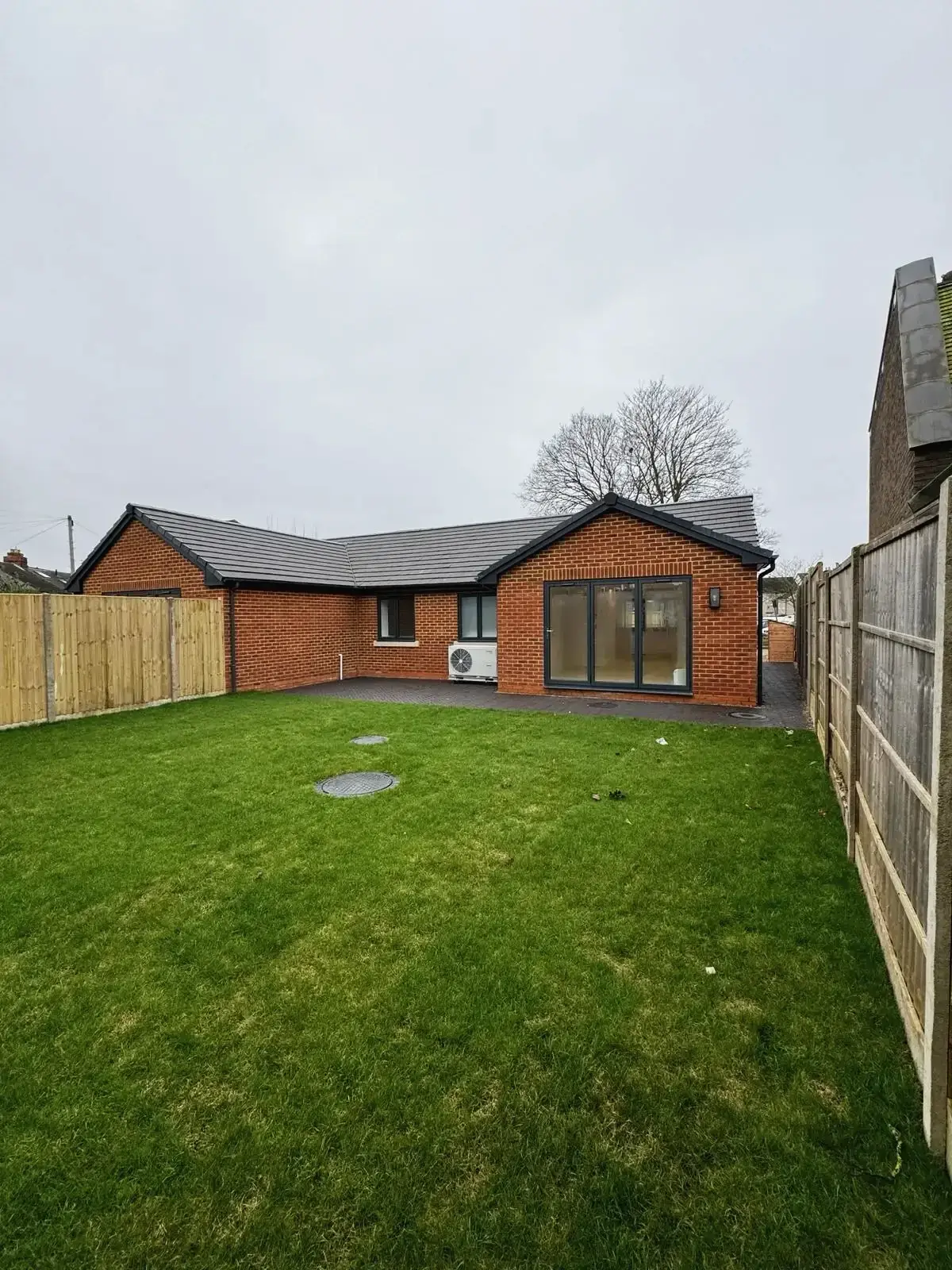 Back view of single-storey home with garden lawn and sliding glass doors