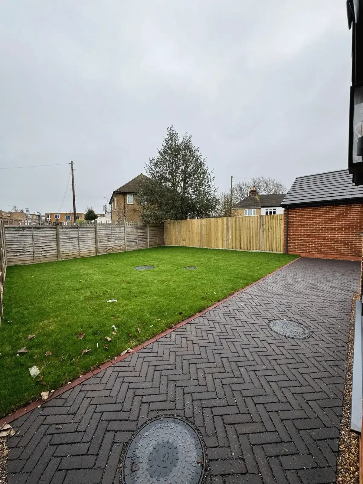 Backyard view of new build property with fenced lawn and brick path