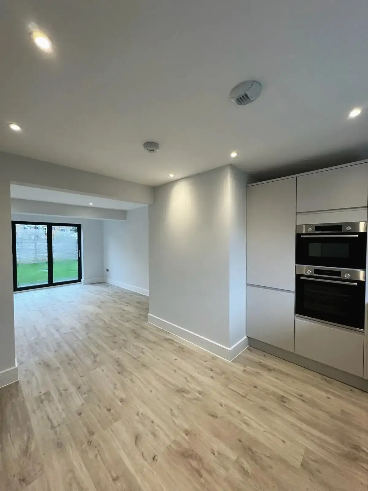 Bright kitchen diner with oak-effect flooring and access to living area to outdoor space