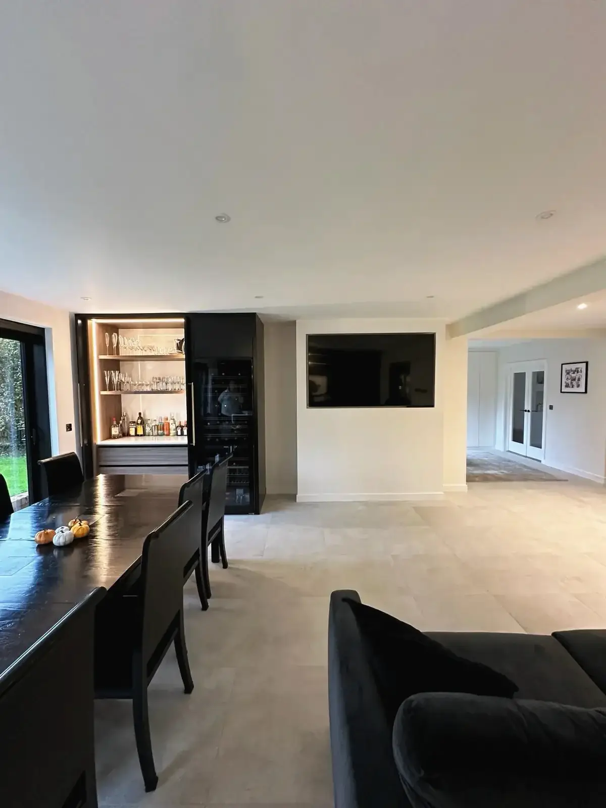 Contemporary home renovation featuring sleek black dining set and bar display