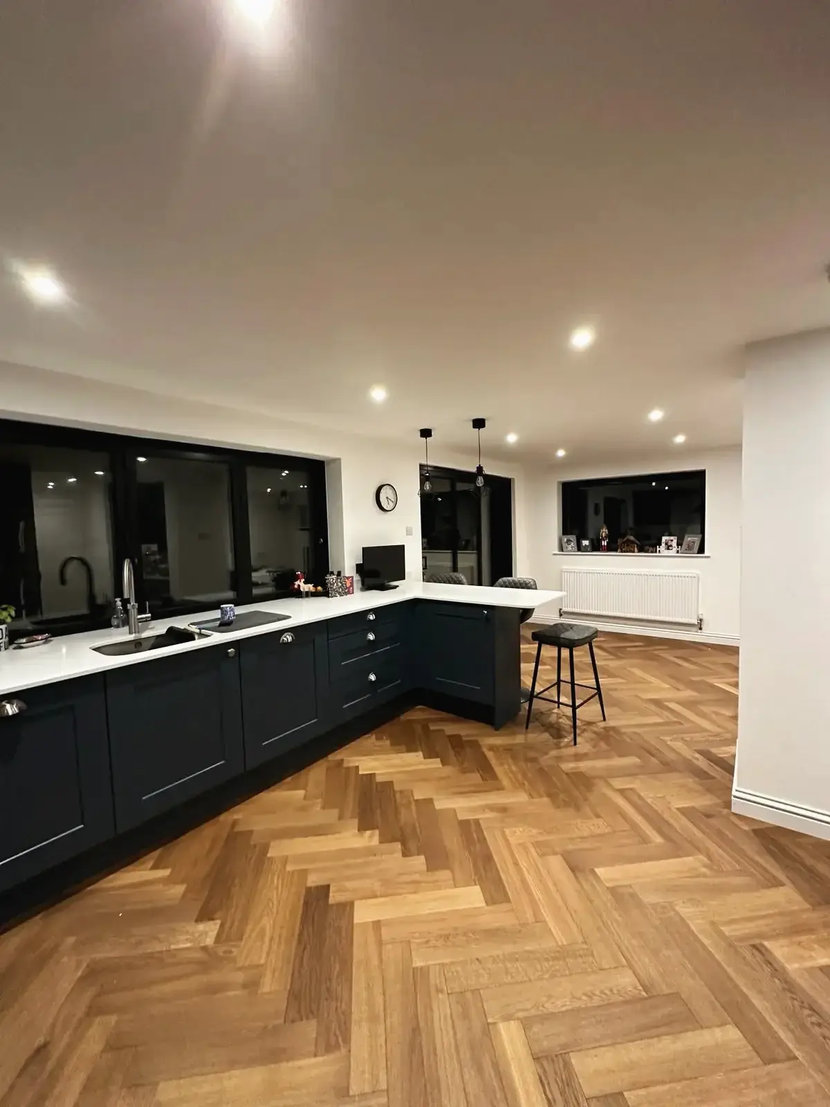 Contemporary open kitchen with bar stools and oak parquet flooring