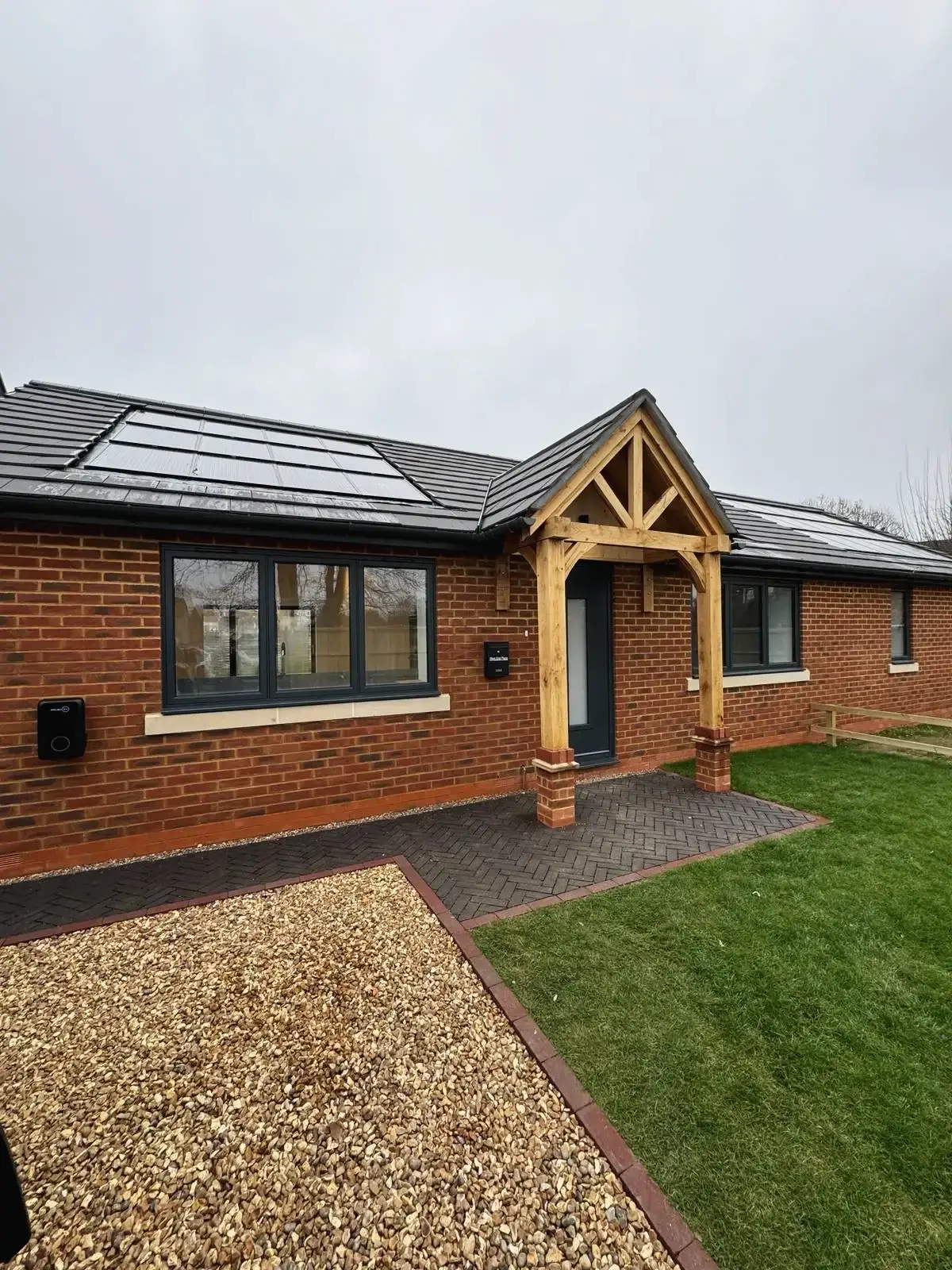 Front side view of energy-efficient home with solar panels and gravel driveway