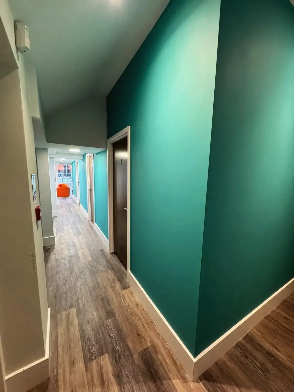 Loft conversion medical hallway view with teal wall by Godman Construction in Chobham