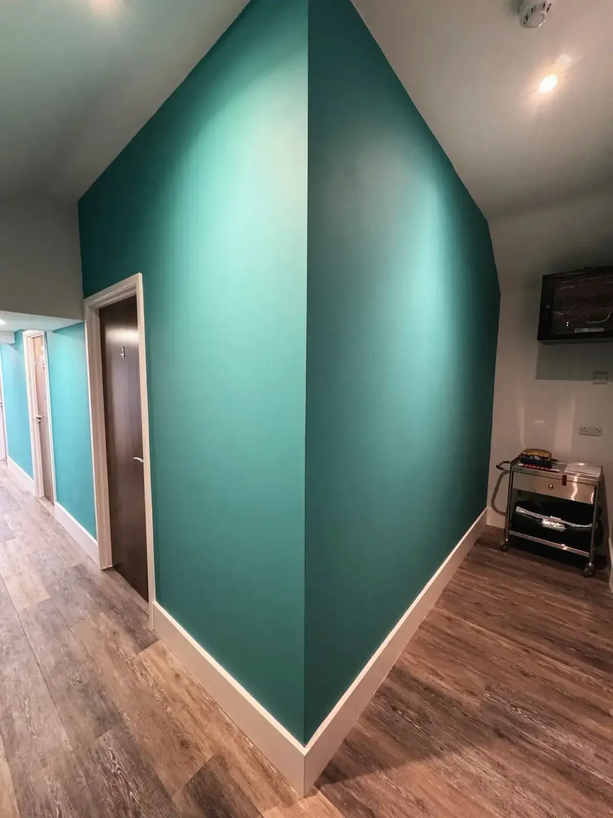Loft conversion medical room corner view with teal wall by Godman Construction in Chobham
