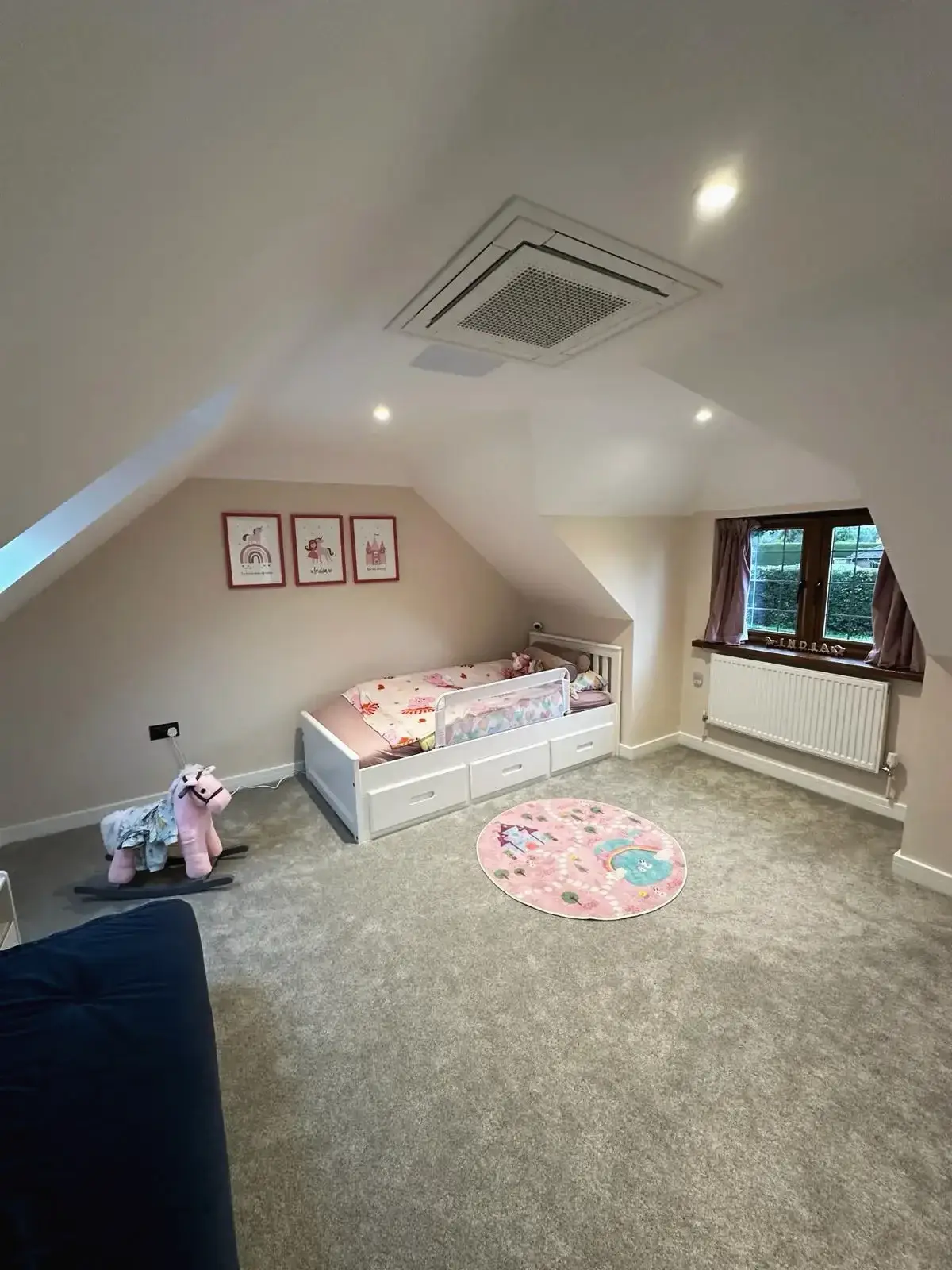 Modern attic kids’ room featuring single bed, storage drawers, and sloped ceiling