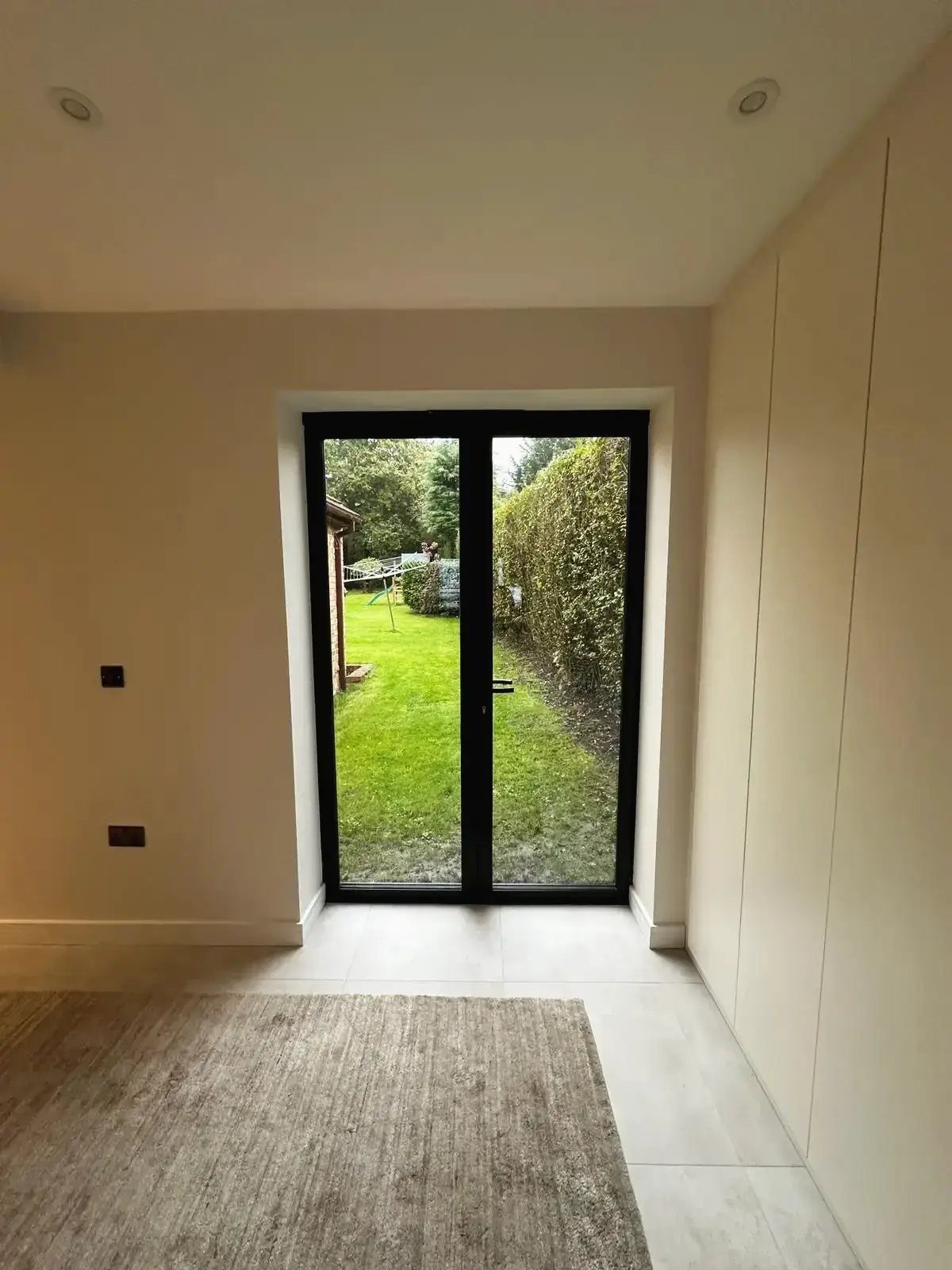 Modern black-framed patio doors leading to garden