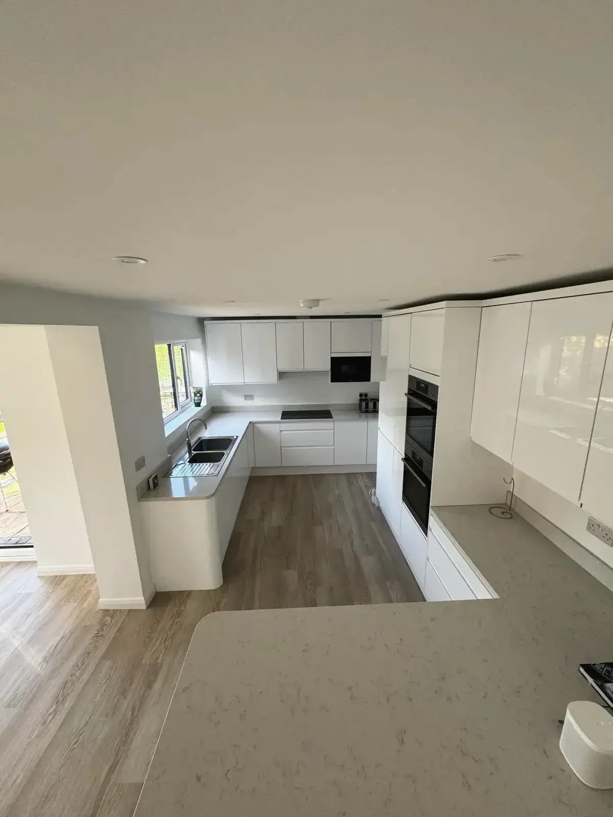 Modern fitted kitchen with built-in oven, island counter and natural light