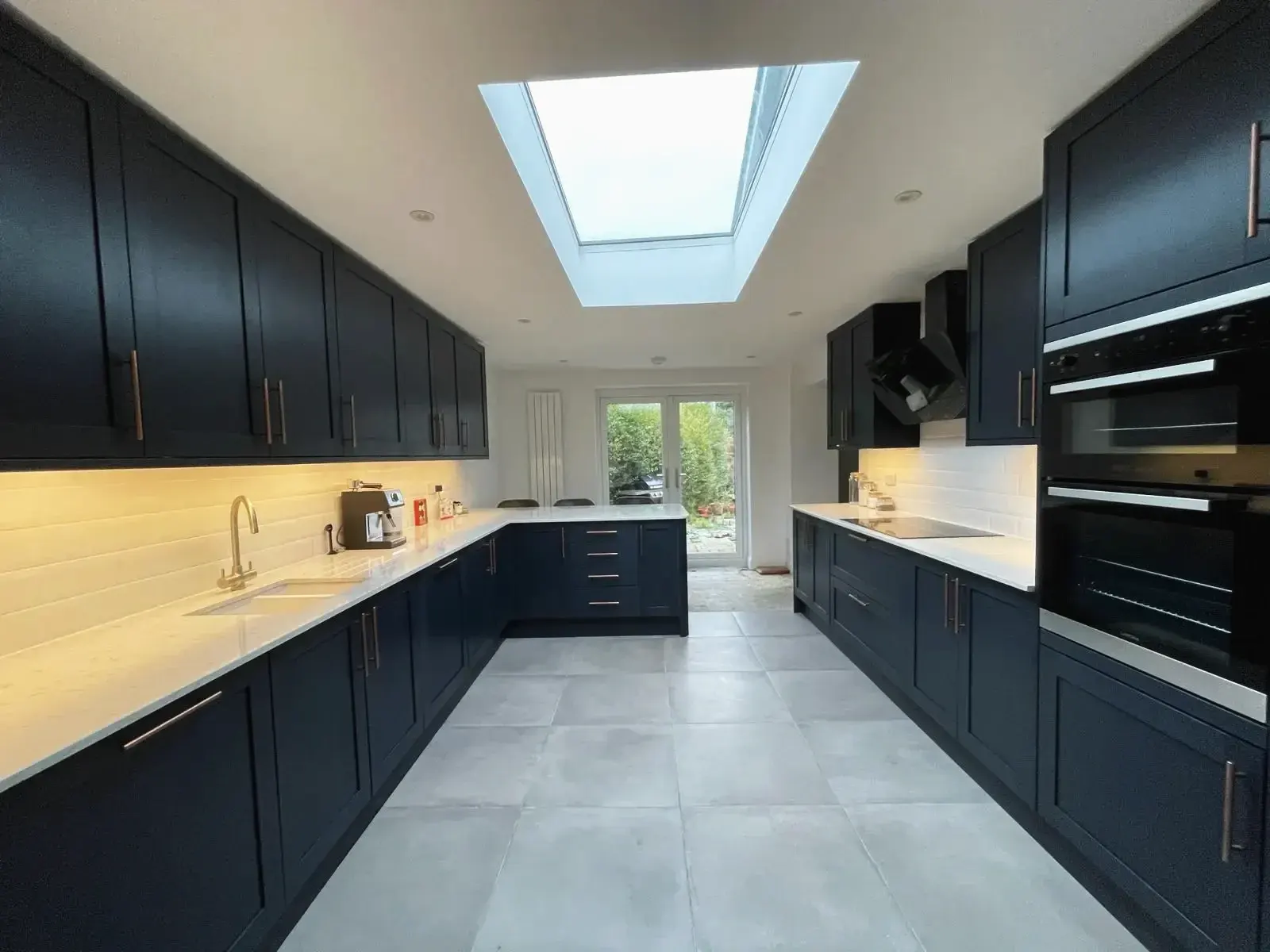 Modern kitchen renovation by a trusted builder in Surrey UK with skylight and dark cabinets