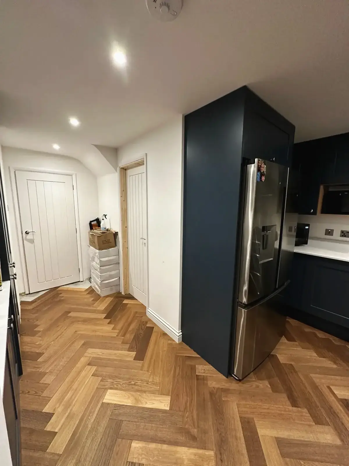 Modern kitchen with herringbone wood flooring and integrated fridge