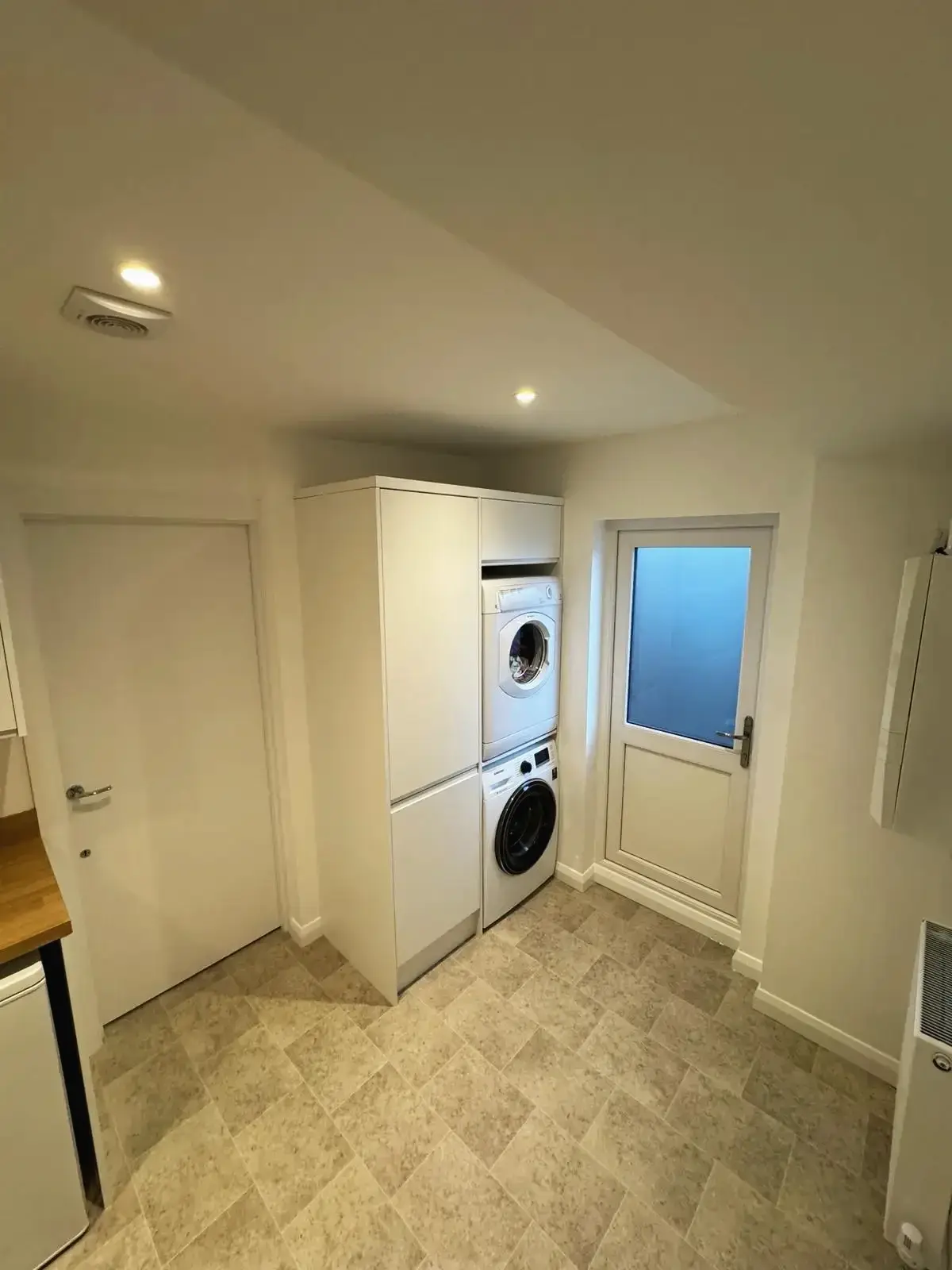 Modern laundry area with integrated washer and dryer beside the kitchen