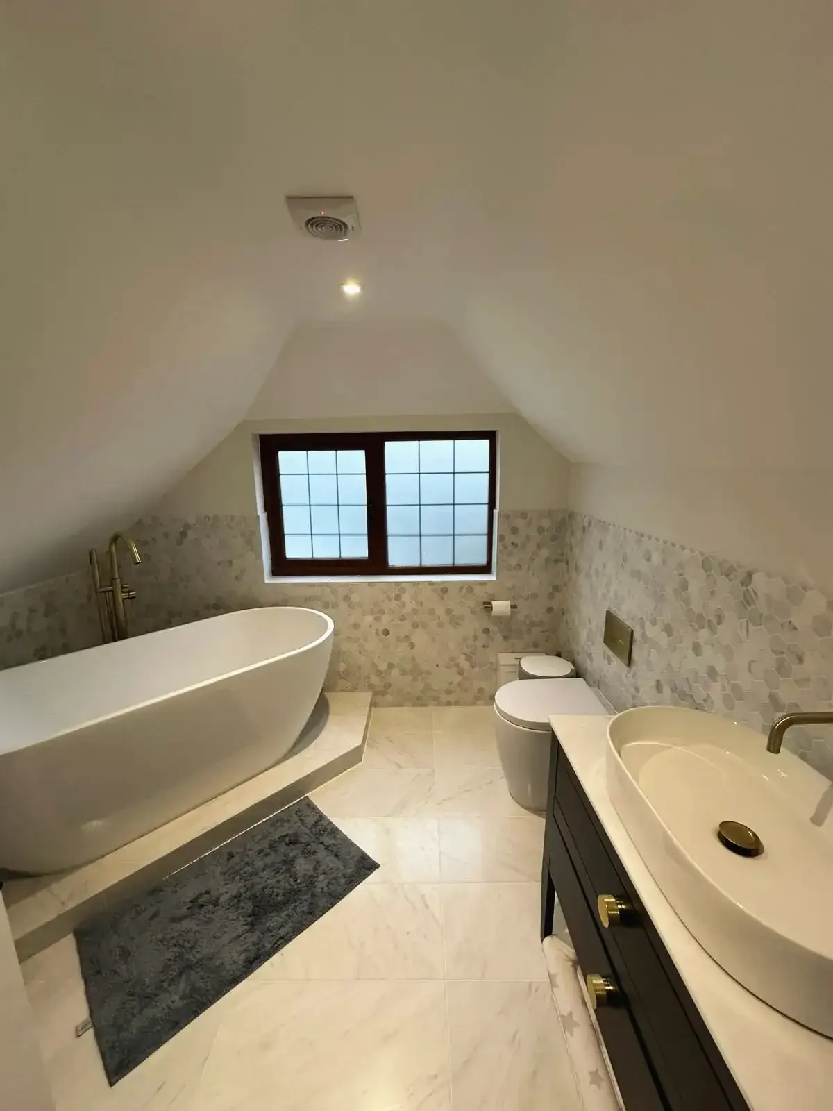 Modern loft bathroom with freestanding bathtub, vanity sink, and marble flooring