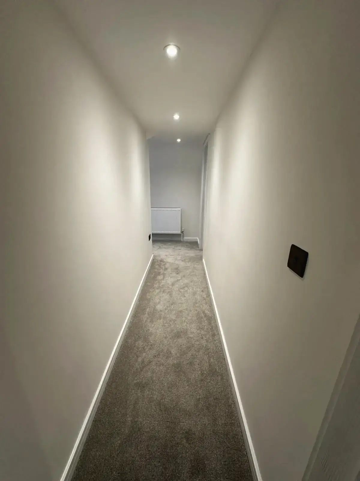 Newly refurbished hallway with fresh carpet and recessed lighting