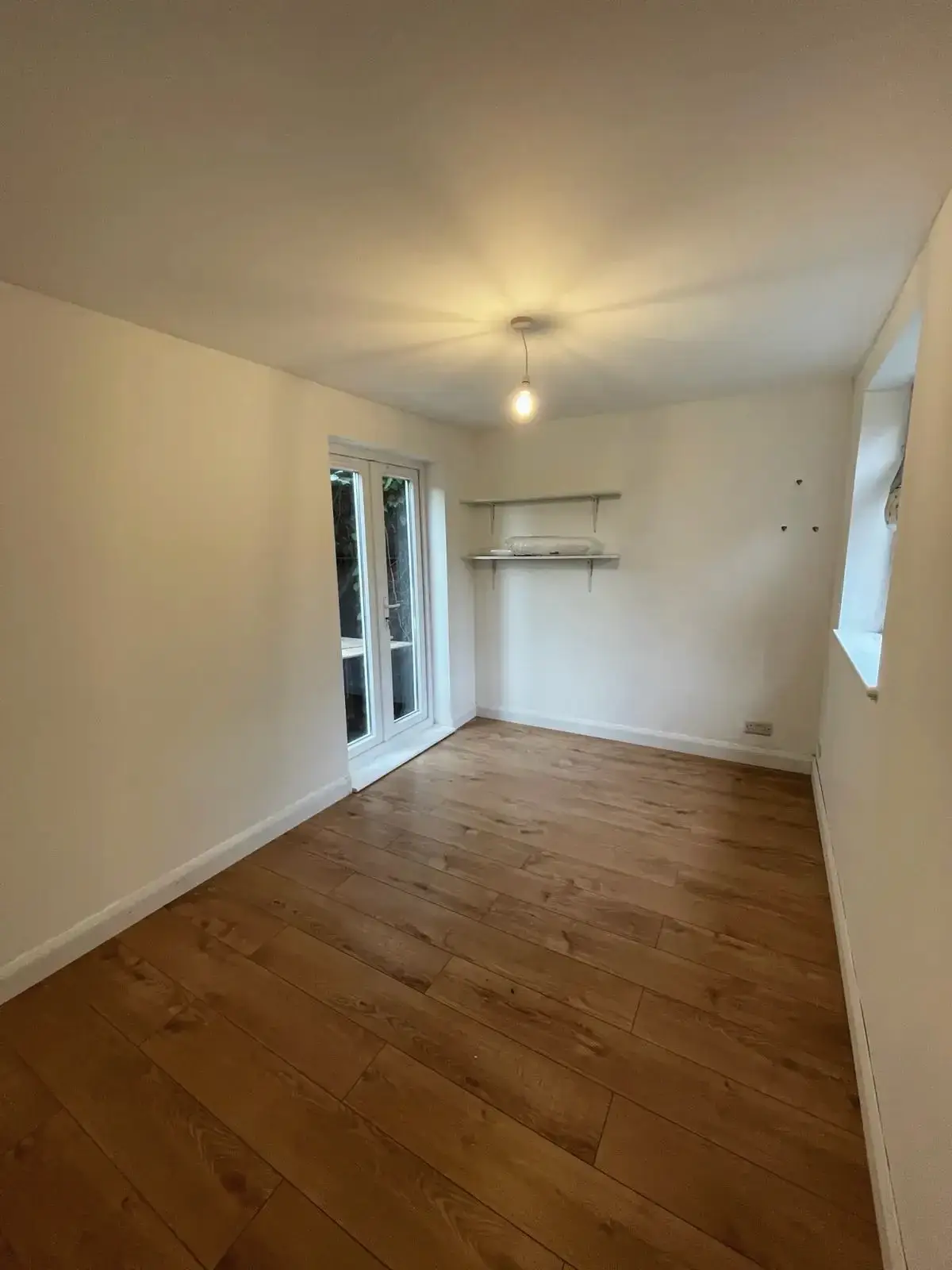 Newly renovated room with wood floor and ceiling light