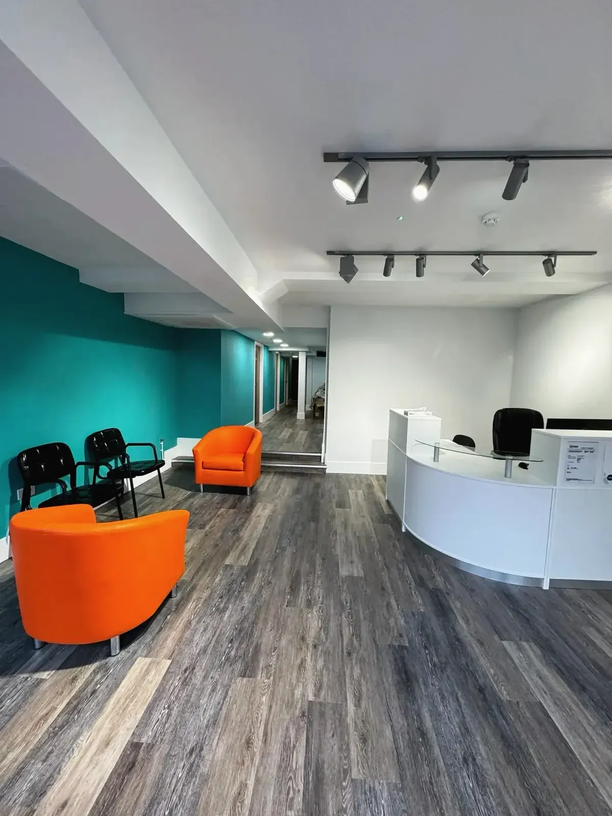 Office reception with track lighting, wooden flooring, and seating area