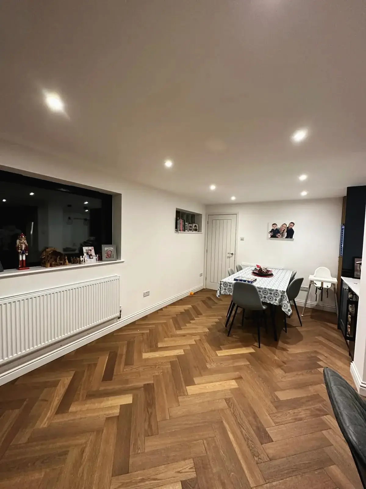 Open-plan dining area with wood parquet flooring and grey dining chairs