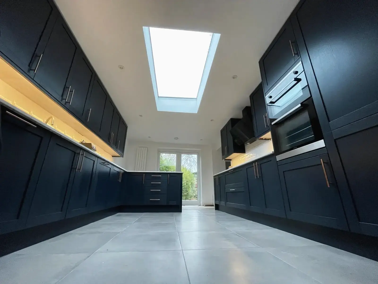 Refurbished kitchen featuring navy units and white countertops