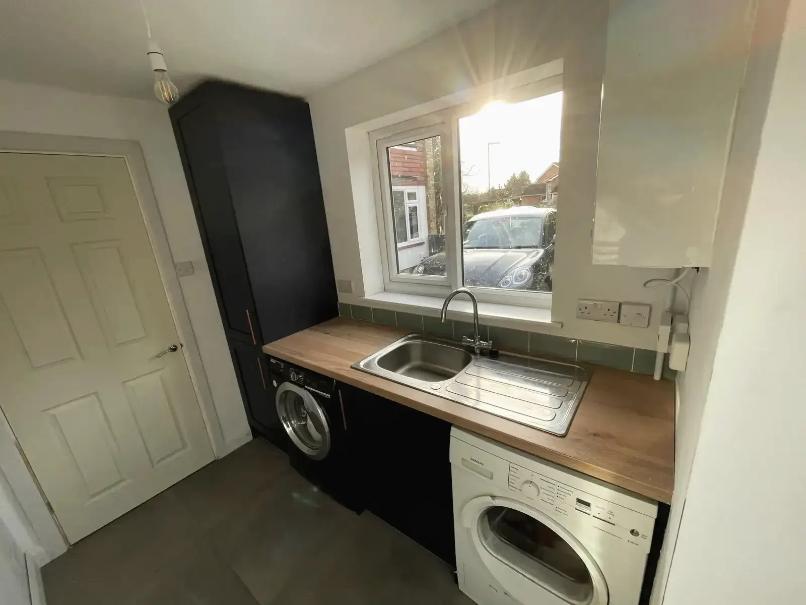 Refurbished laundry room with sink, storage, and appliances