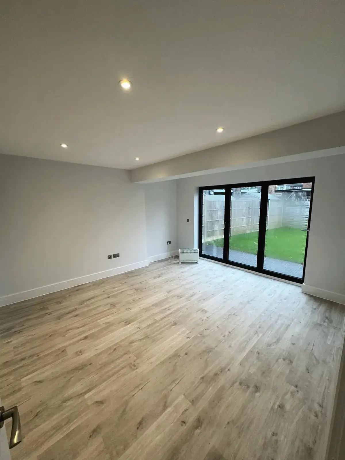 Refurbished open-plan living space featuring light wood flooring and sliding patio doors