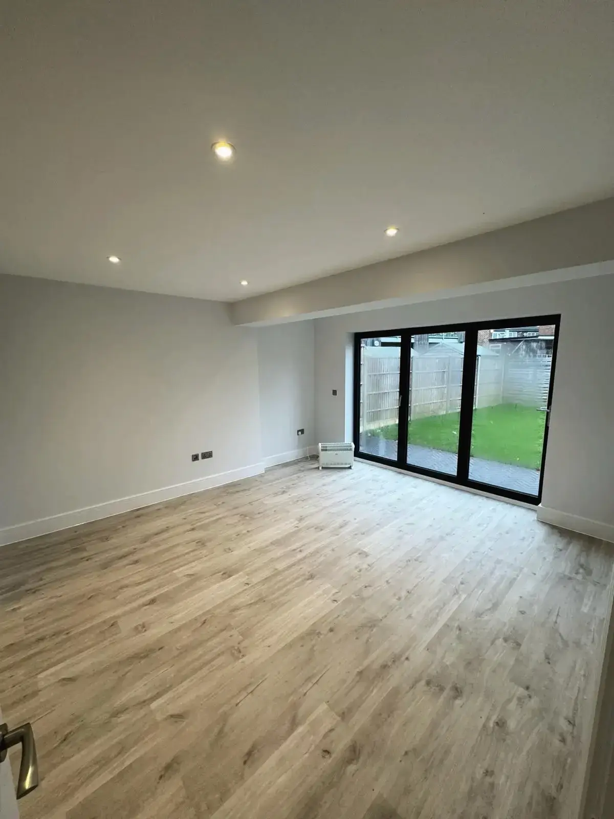 Refurbished open-plan living space featuring light wood flooring and sliding patio doors