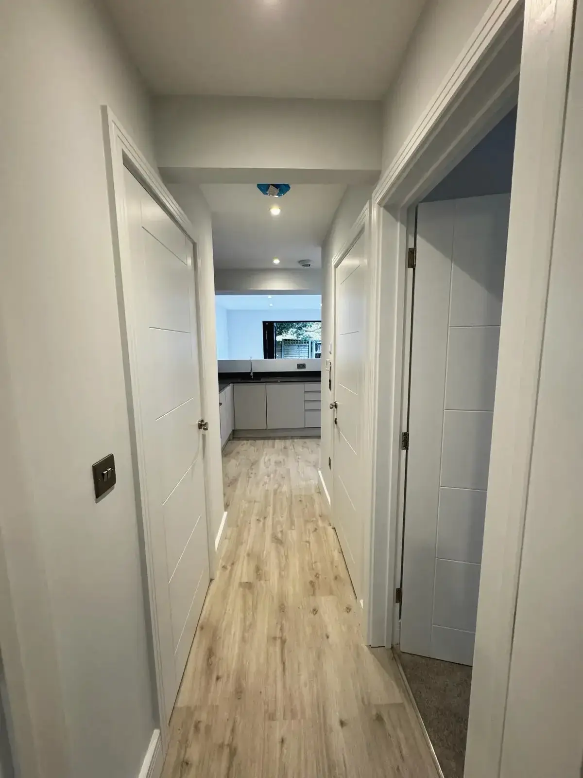 Renovated home hallway with white walls and access to kitchen area