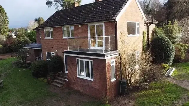 Residential property renovation in Guildford featuring glass balcony extension