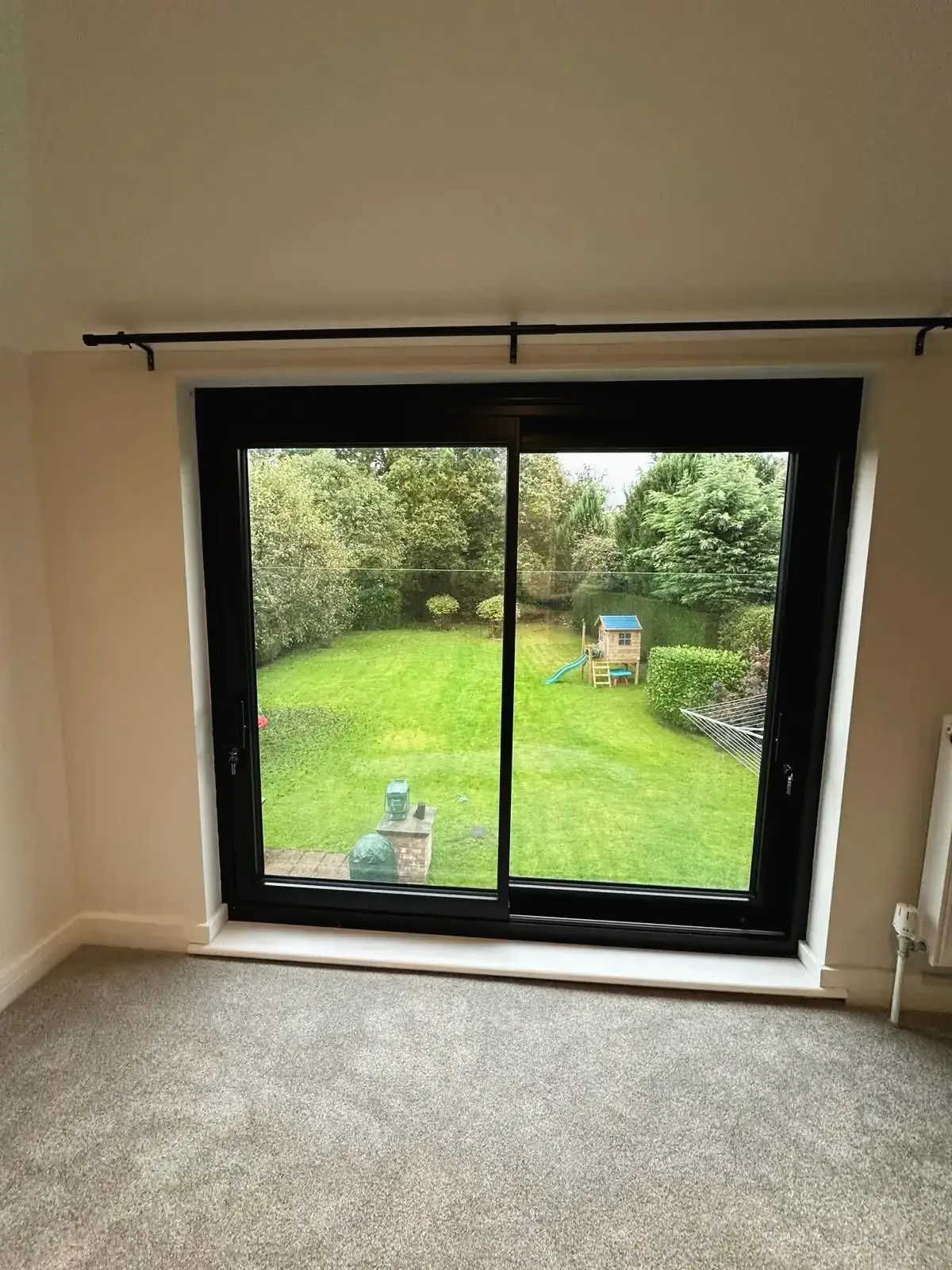 Sliding patio doors with black frame overlooking landscaped garden