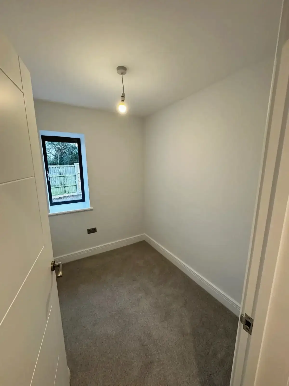 Small renovated bedroom with carpet flooring and window view