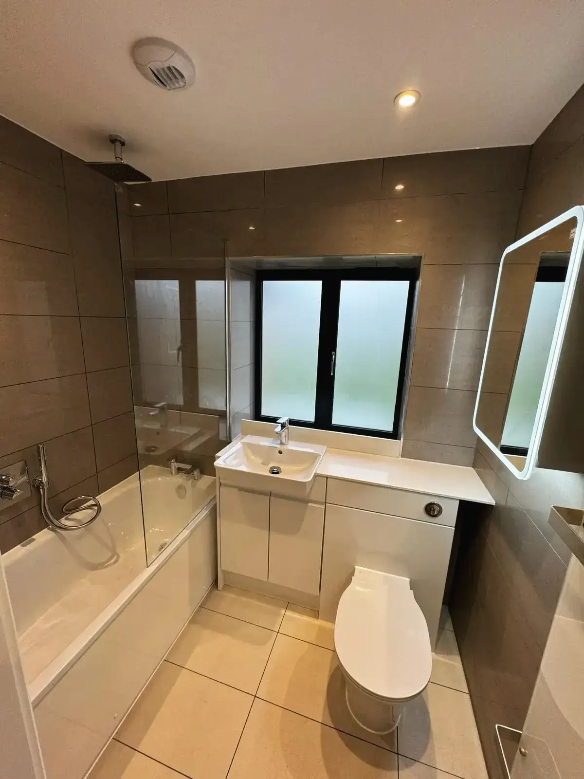 Space-saving bathroom renovation with fitted vanity unit and tiled walls