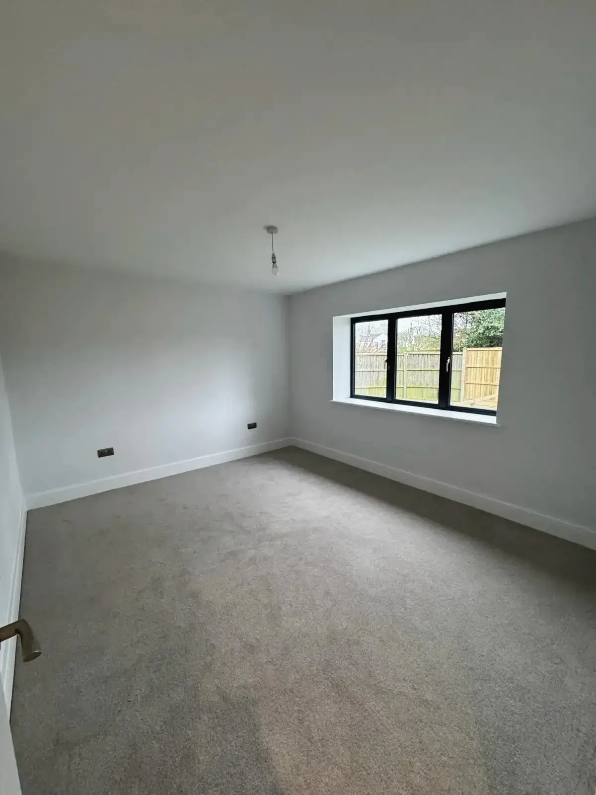 Spacious bedroom interior with carpet flooring and white walls