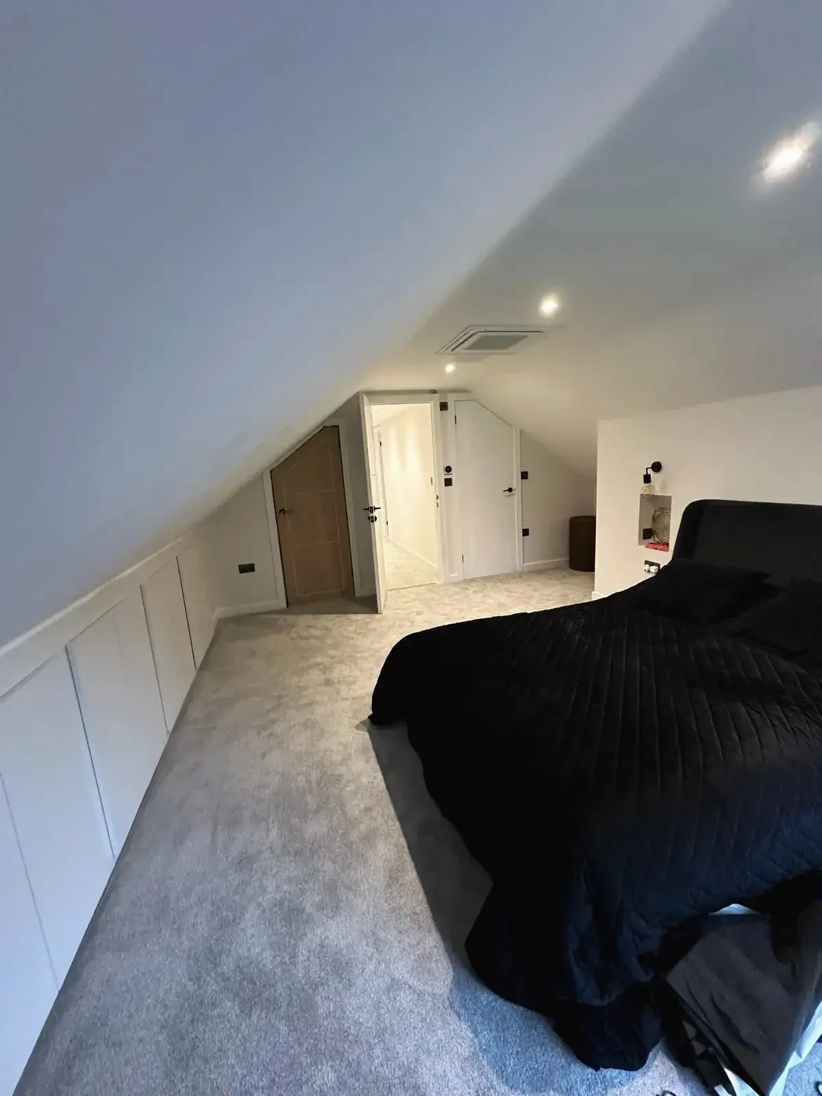 Spacious loft conversion bedroom with sloping roof and fresh carpeting