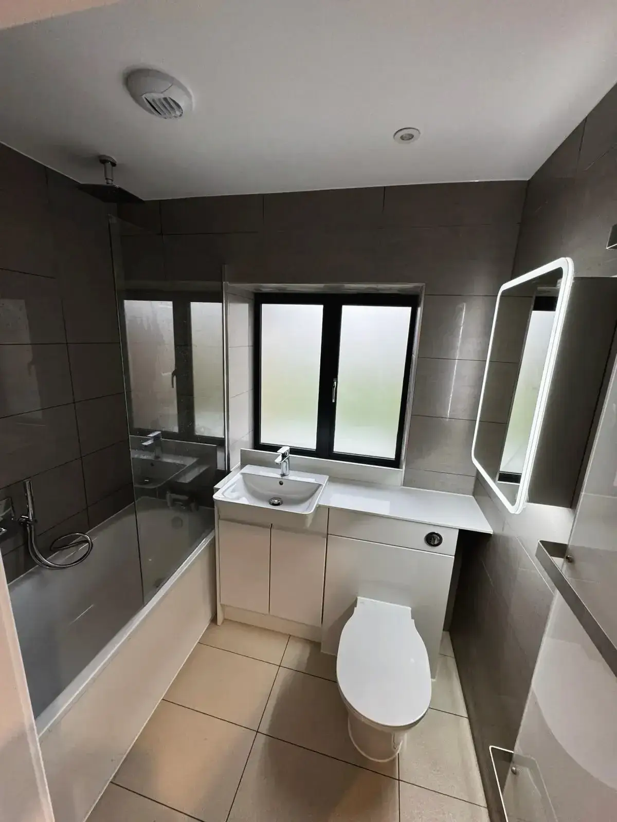 Stylish bathroom remodel featuring compact layout, bath with shower, and wall tiles