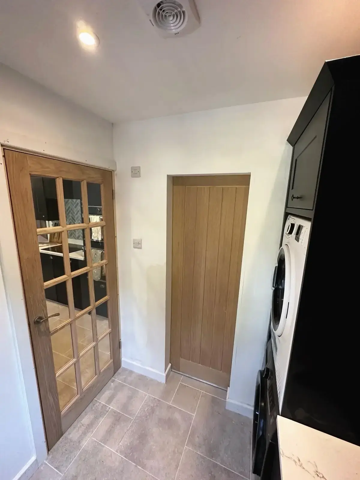 Utility room with stacked washer dryer and wooden doors
