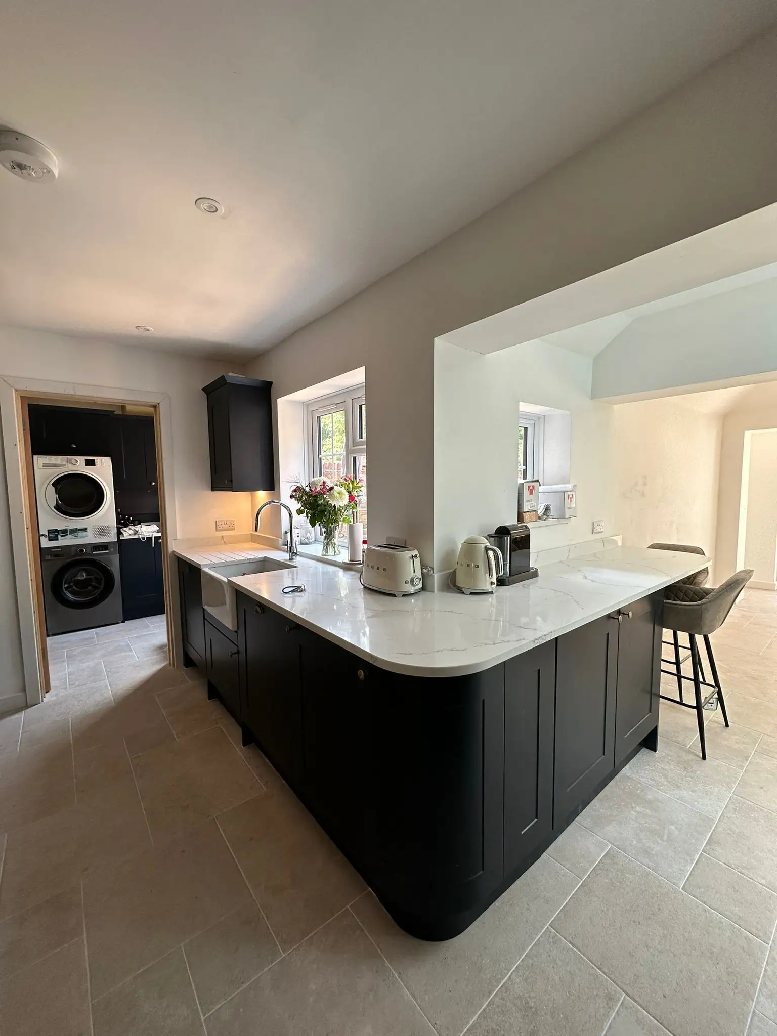 Modern kitchen renovation with black cabinets, white marble countertop island, and open-plan layout by Godman Construction