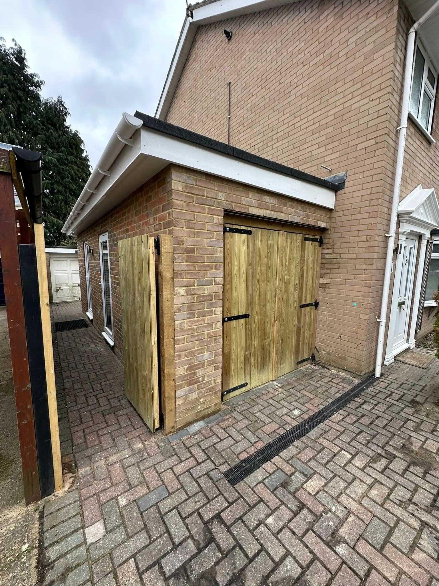 Brick side extension with timber doors and pitched roof built by Godman Construction.