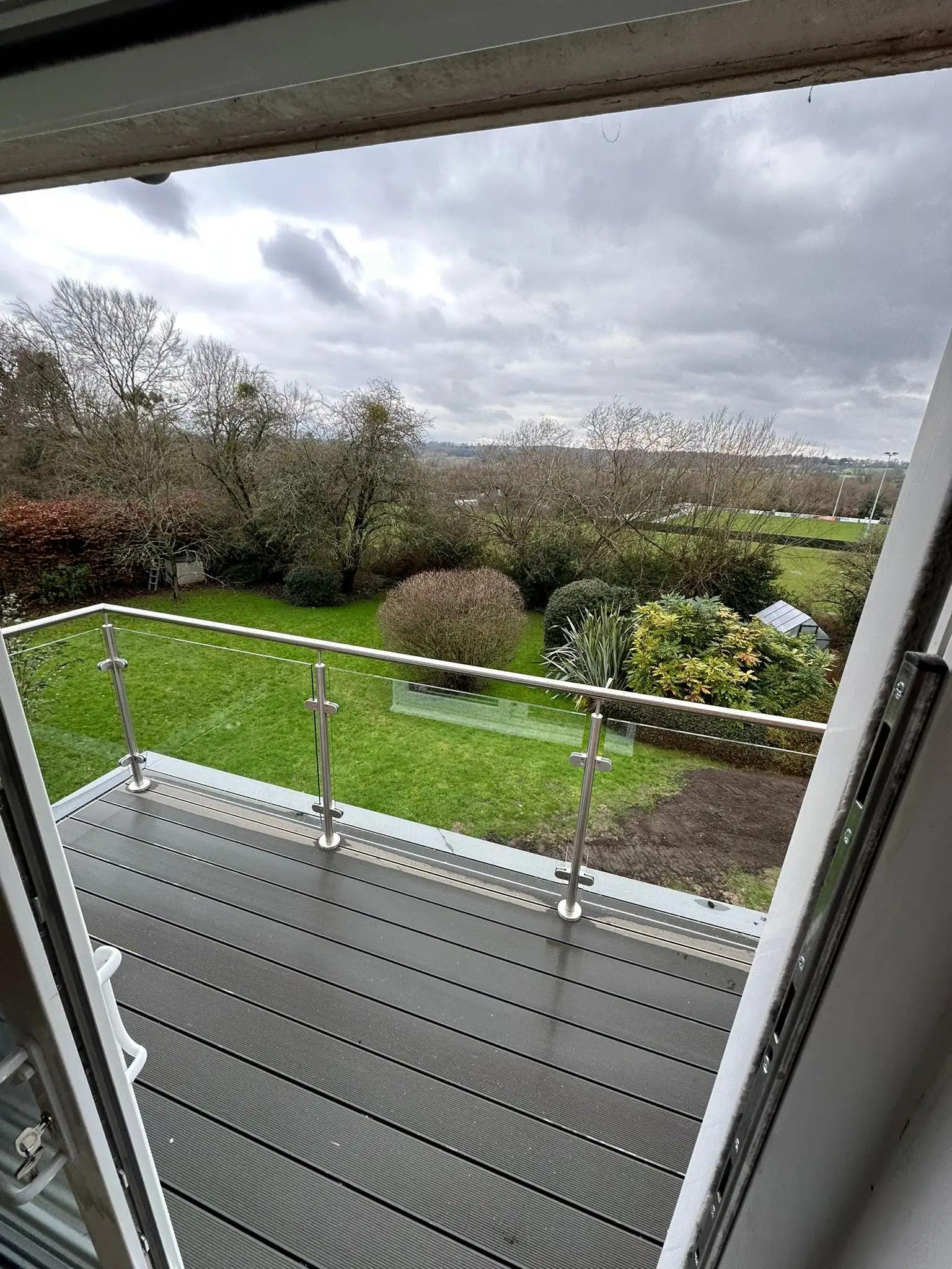 Modern balcony with glass balustrade overlooking garden, built by Godman Construction.