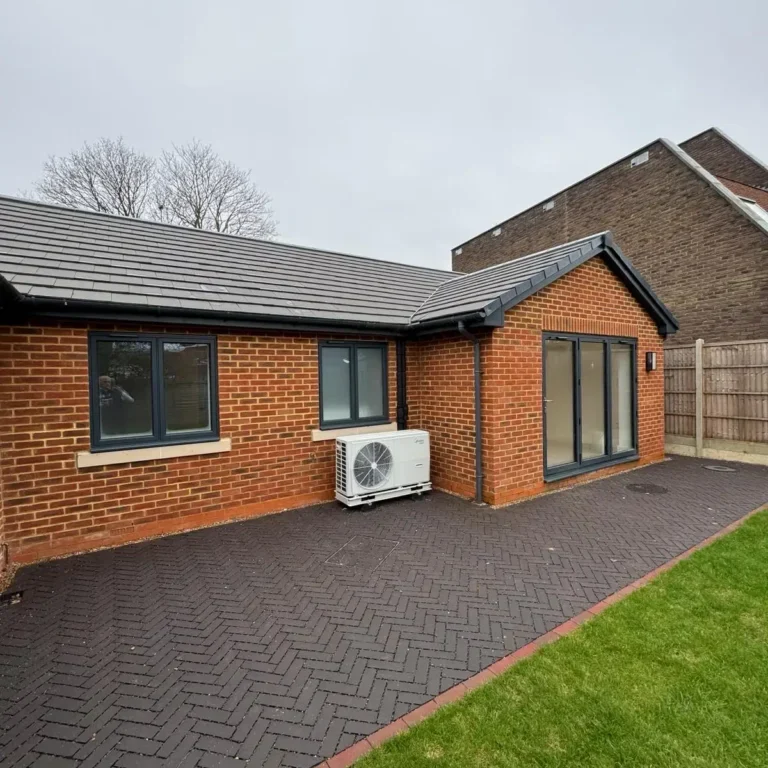 Back exterior of new build property with paved patio and garden view by Godman Construction