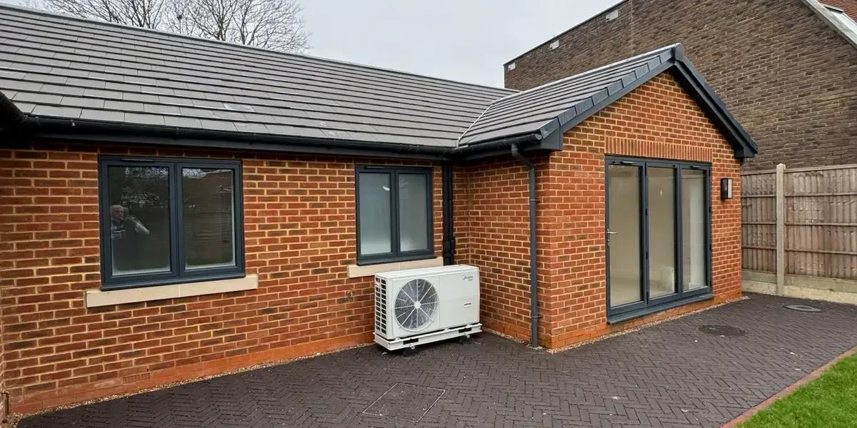 Back exterior of new build property with paved patio and garden view by Godman Construction