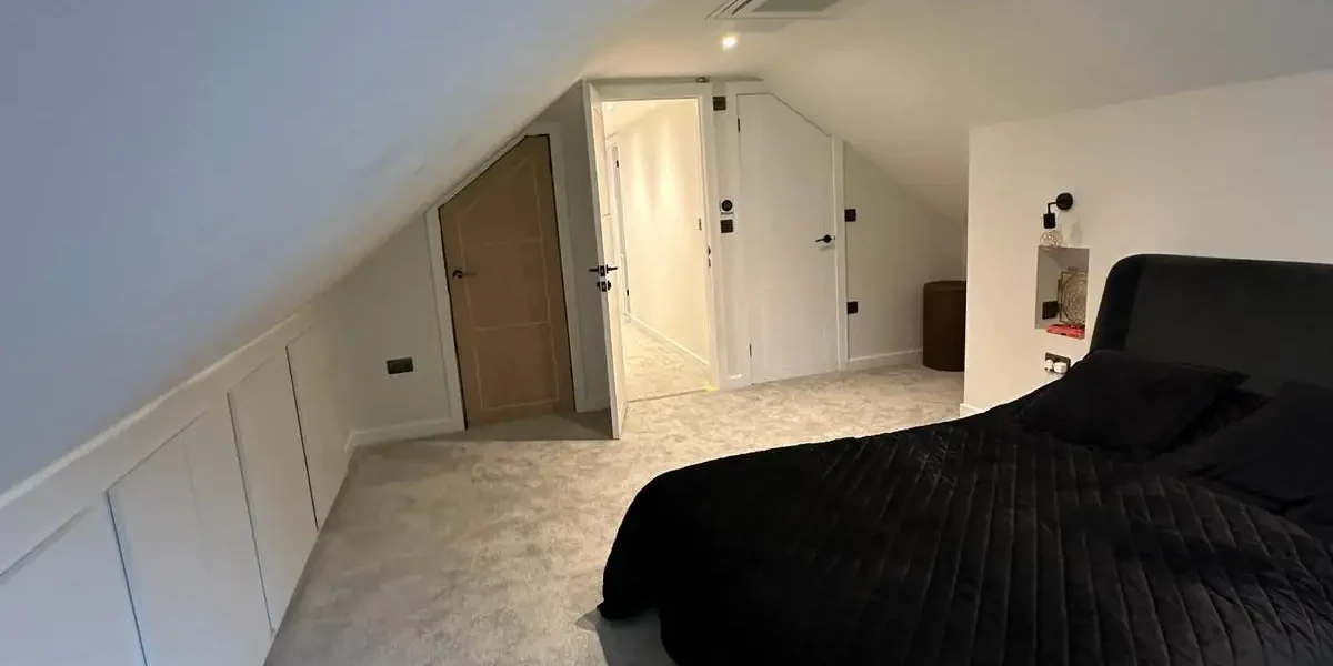 Spacious loft conversion bedroom with ensuite - sloping roof and fresh carpeting by Godman Construction