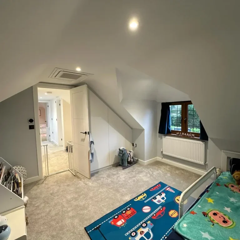 Loft conversion children’s bedroom with sloped ceiling and fitted storage by Godman Construction