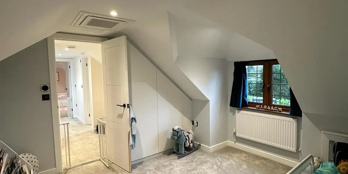 Loft conversion children’s bedroom with sloped ceiling and fitted storage by Godman Construction