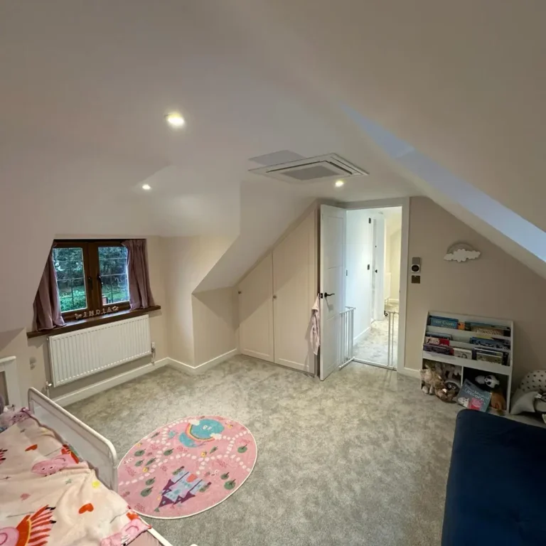 Spacious loft conversion children’s bedroom with fitted storage and soft carpeting by Godman Construction