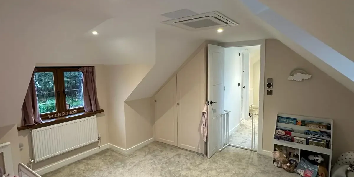 Spacious loft conversion children’s bedroom with fitted storage and soft carpeting by Godman Construction