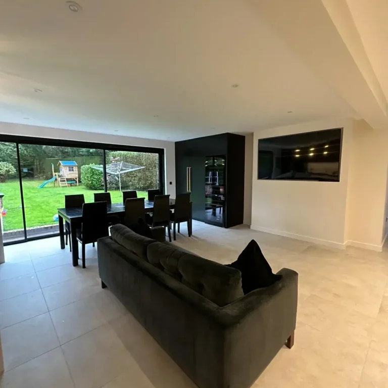 Open-plan lounge and dining area with natural light from sliding doors by Godman Construction