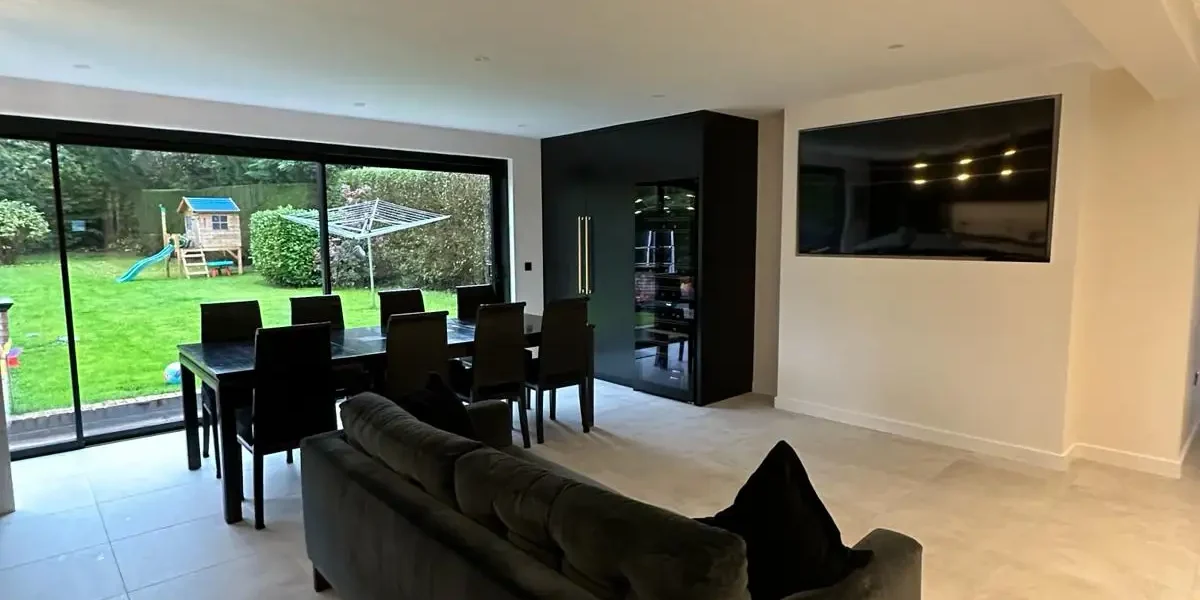 Open-plan lounge and dining area with natural light from sliding doors by Godman Construction
