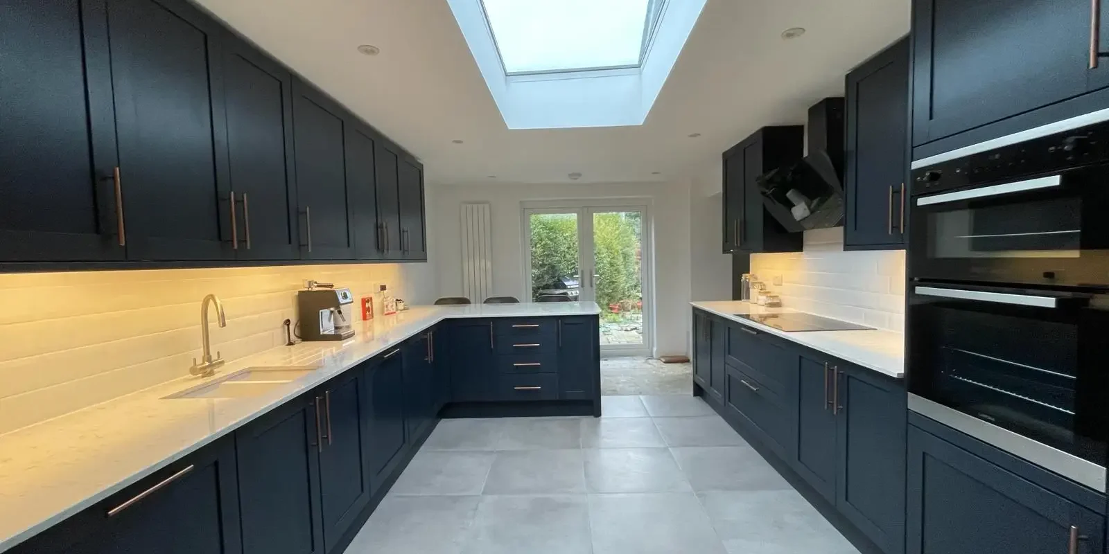Modern kitchen renovation by a trusted builder in Surrey UK with skylight and dark cabinets from Godman Construction.